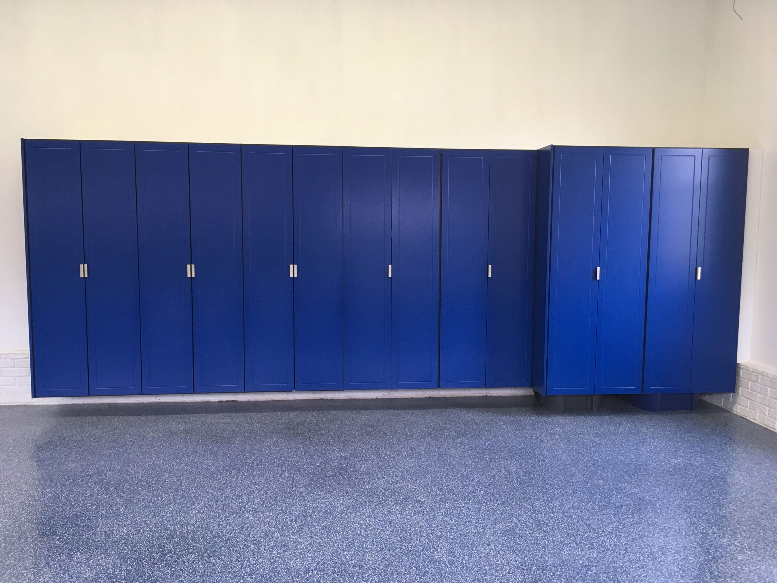 Blue custom garage cabinets with drawers and a dark countertop